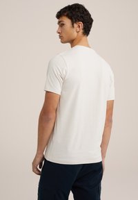 Tricou scurt cu mânecă scurtă de culoare bej deschis, cu guler rotund, având o textură netedă și un croi drept. Vedere din spate care evidențiază un design simplu.