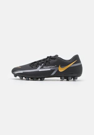 Crampon de football Nike Phantom noir avec swoosh doré, accents argentés et crampons moulés pour terrain ferme.