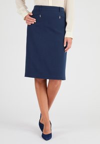 Jupe crayon marine au design ajusté, avec deux poches zippées à l'avant et un ourlet juste au-dessus du genou. Tissu lisse avec une légère brillance.