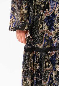 Robe à manches longues avec un motif floral cachemire en bleu marine, noir et crème, avec une taille en dentelle noire texturée et une jupe fluide.