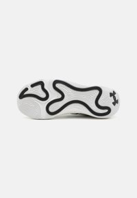 Witte sneakersole met een golvende zwarte rubberen patroon, voorzien van textuurlijnen en het Under Armour-logo op de buitenrand.
