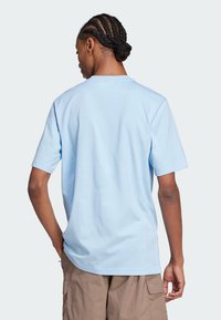 Tricou scurt cu mânecă scurtă de culoare bleu deschis, fabricat din bumbac, cu un croi relaxat și guler rotund, asortat cu pantaloni scurți cargo kaki.