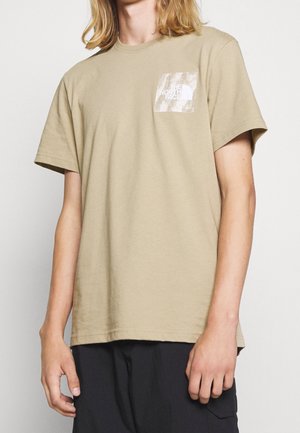 Beiges Baumwoll-T-Shirt mit kurzen Ärmeln, mit einem Brusttaschenaufdruck des The North Face Logos in Weiß auf strukturiertem Stoff.