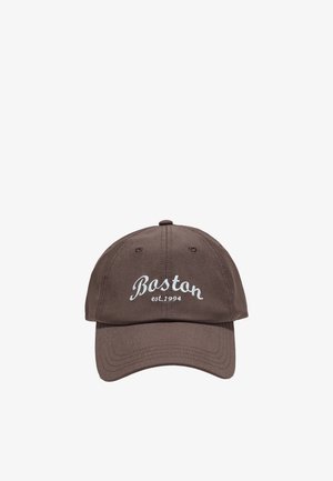 Casquette de baseball marron avec texte blanc brodé « Boston est. 1994 » sur le devant, avec des œillets de ventilation cousus.