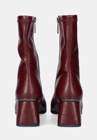 Botas de tobillo de imitación de cuero burdeos con una textura suave, tacones de bloque de altura media, punteras puntiagudas y cierres de cremallera lateral.