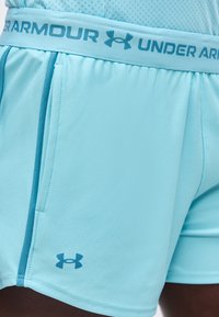 Ανοιχτού μπλε αθλητικό σορτς Under Armour με ελαστική μέση και πλαϊνές τσέπες, με το όνομα και το λογότυπο της εταιρείας σε σκουρότερο μπλε χρώμα.