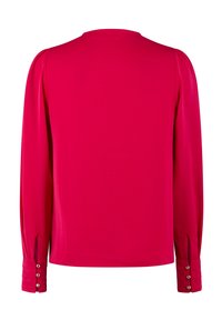 Long-sleeve top in fuchsia, featuring a round neckline, gathered shoulder seams, and buttoned cuffs with small cutouts at the wrists.