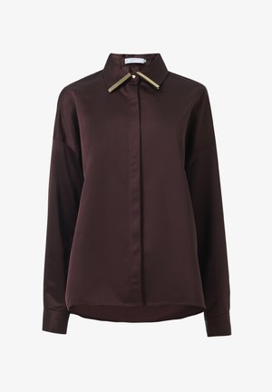 Chemise bordeaux à boutons en tissu lisse avec un col pointu et des accents dorés sur le col. Elle présente des manches longues et une coupe décontractée.