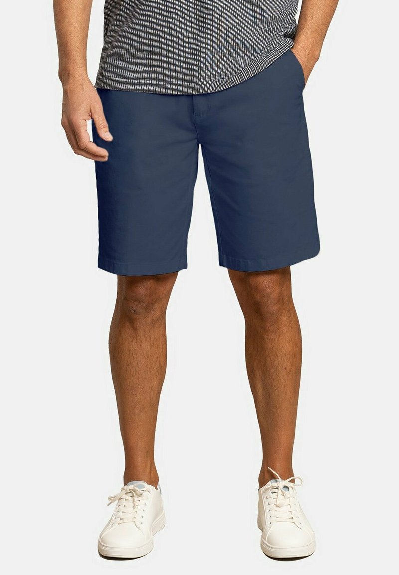 Pantalones cortos azul marino hechos de un material ligero con una textura suave. Diseño sencillo, hasta la rodilla, combinados con zapatillas blancas.