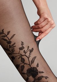 Collant neri trasparenti con un motivo floreale in tonalità scure, caratterizzati da una texture liscia e delicati dettagli sui lati.