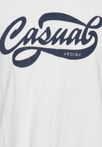 Balta medvilninė marškinėliai su dideliu tamsiai mėlynu raižiniu, užrašu "Casual Friday", per visą priekį. Minkšta struktūra, laisvas fasonas.