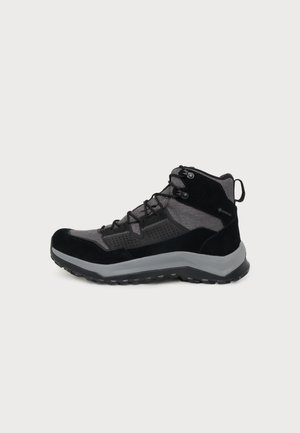 Chaussure de randonnée noire et grise à tige mi-haute, avec fermeture à lacets, cheville rembourrée, semelle à crampons et semelle épaisse grise, vue de côté.