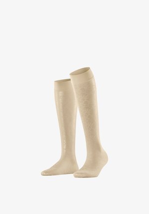 Beige compressiekousen tot aan de knie met subtiel gestructureerd patroon, elastische bovenbanden, ontworpen voor medisch of sportief gebruik.