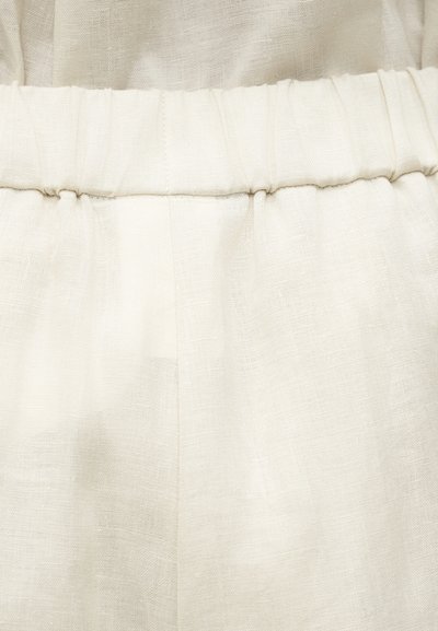 Κοντινό πλάνο ελαστικής μέσης σε μπεζ χρώμα, σε ελαφρύ παντελόνι από λινό ύφασμα με υφή.