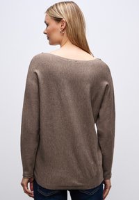 Brązowy sweter z dzianiny o szerokim dekolcie, długich rękawach i lekko zaokrąglonym dołem. Gładka faktura, casualowy design odpowiedni do warstwowego noszenia.