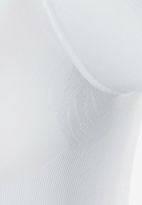 Vêtement de compression blanc avec des motifs en tricot texturé et des zones lisses, conçu pour offrir un soutien avec une finition sans couture.