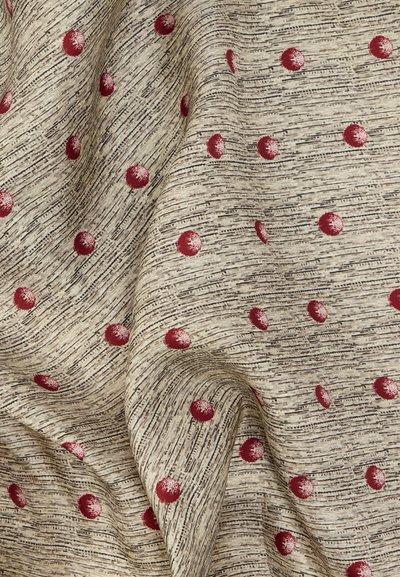 Μπεζ ύφασμα με ανάγλυφες οριζόντιες μαύρες γραμμές και διάσπαρτες κόκκινες πουά, εμφανιζόμενο με φυσικές πτυχώσεις και ρίξεις.