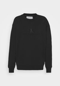 Černá mikina vyrobená z měkké tkaniny, s kulatým výstřihem, dlouhými rukávy a vyraženým logem "CALVIN KLEIN JEANS" vpředu.