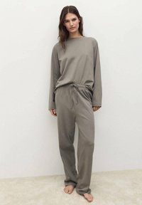 Conjunto de top de manga larga gris y pantalones con cordón, fabricado con tela suave. Corte relajado con un diseño simple, sin patrones ni detalles metálicos.