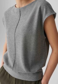 Grijs T-shirt met korte mouwen en een ronde hals, van een textuurstof met een subtiele centrale naad langs de voorkant. Verzacht en ontspannen pasvorm.