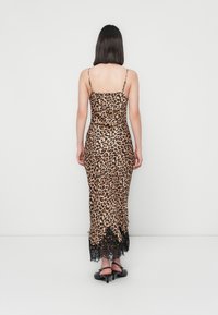 Vestido maxi de estampa leopardo com alças finas, bainha de renda e silhueta ajustada. Tecido suave com um padrão animal em tons de castanho e preto.