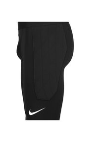 Leggings atletici neri con un pannello posteriore trapuntato e il logo Nike bianco. Realizzati in materiale elastico per comfort e flessibilità.