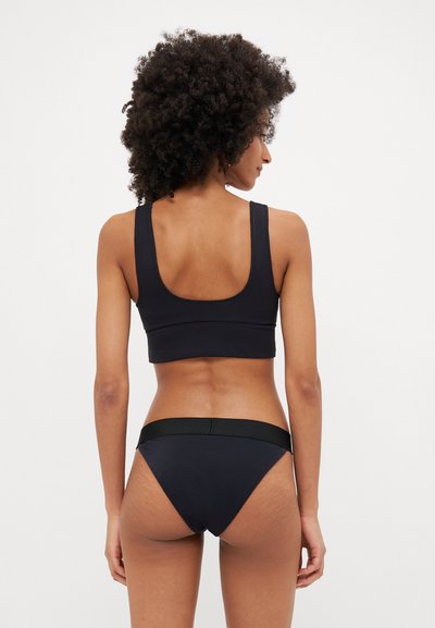 Schwarzer Sport-BH und passende Bikinislips, gefertigt aus glattem Material. Der BH hat breite Träger, während der Bikini einen schmalen Bund aufweist.