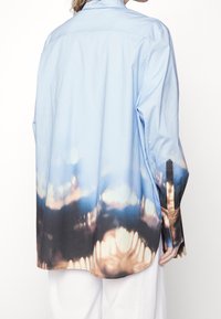 Light blue button-up shirt with a gradient pattern transitioning to dark brown at the bottom, featuring long sleeves and a relaxed fit.