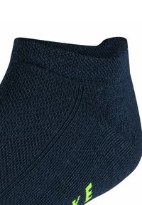 Calzino alla caviglia blu navy realizzato in tessuto testurizzato, con una vestibilità aderente e un dettaglio del logo verde brillante vicino alle dita.