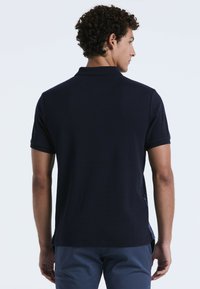 Marineblauwe polo met korte mouwen, voorzien van een gemêleerd zijpaneel detail en een klassieke kraag. Materiaal lijkt glad en lichtgewicht.