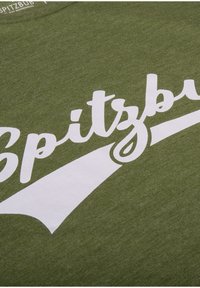 Olivengroene katoenen t-shirt met opvallende witte tekst die "Spitzbug" zegt, met daaronder een gebogen witte grafiek.