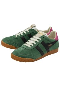 Green suede sneakers featuring black side stripes, white laces, and a pink heel accent. Textured gum rubber sole for grip. Brand logo on tongue.
