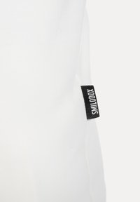 Weißer Stoff mit einer glatten Textur hat an der Seite ein schwarzes Etikett mit der Aufschrift "SMILOOX", das die Produktmarke kennzeichnet.