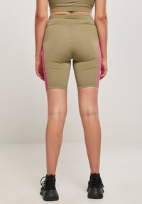 Maslinasto zelene hlače kratkog kroja s ružičastim bočnim panelima, izrađene od rastezljivog materijala, s prilagođenim dizajnom i dužinom do sredine bedra.