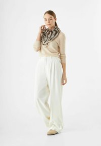 Beige gebreid sweater, witte wijde broek, en een bruin-grijs gestreepte sjaal. De outfit toont zachte texturen en neutrale kleuren.