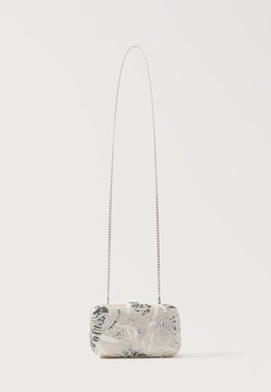 Petit sac clutch rectangulaire avec perles florales argentées et une fine bandoulière chaîne sur un fond clair uni.