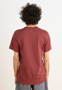 Mørkerød bomulds t-shirt med korte ærmer og rund hals, med en glat tekstur og afslappet pasform, vist fra ryggen.