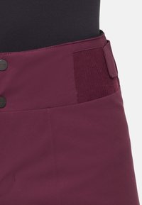 Høj talje burgunder nederdel med sorte knapper og tekstureret elastisk sidepanel for en tæt og justerbar pasform.