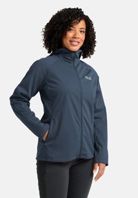 Giacca softshell blu scuro con colletto alto, chiusura con zip frontale, tasche laterali e polsini elasticizzati. Presenta un logo discreto sul petto.