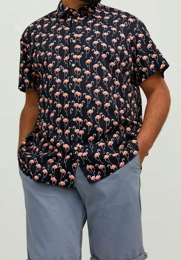 Camisa de manga corta, tipo polo, con fondo azul marino y un patrón de flamencos rosas, hecha de tela ligera. Corte casual con cuello.
