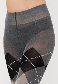 Leggings grigi a fantasia con un motivo argyle composto da diamanti neri, bianchi e grigio chiaro. Texture liscia e cintura elastica.