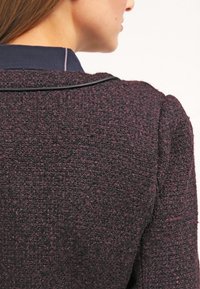 Tmavě fialový texturovaný pletený oděv s límečkem, s kontrastním námořnickým límcem a jemným lemováním.