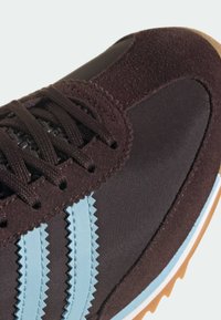 Μαρόν αθλητικό παπούτσι με υλικά από σουέντ και νάιλον, με ανοιχτό μπλε ρίγες και σόλα από καουτσούκ gum. Υπόστρωμα με υφή και κλείσιμο με κορδόνια.