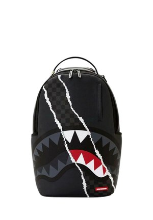 Mochila negra con un diseño de boca de tiburón que muestra dientes blancos y rojos y un patrón de cuadros con dos tiradores de cremallera plateados en la parte superior.