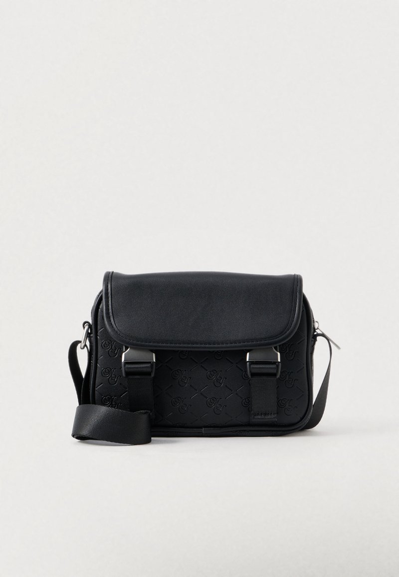 Borsa a tracolla nera in pelle liscia con motivo in rilievo. Presenta una chiusura a pattina, una tracolla regolabile e dettagli in metallo argentato.