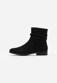 Bottines en suédine noire avec un design supérieur froncé, bout rond et petit talon carré. Texture lisse avec une silhouette décontractée.