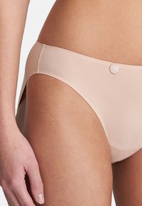 Nackte Bikiniunterteile aus glattem, dehnbarem Stoff. Sie verfügen über ein hochgeschnittenes Design mit einem kleinen dekorativen Knopf an der Seite.