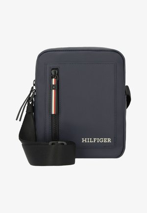 Navy blue crossbody bag with a textured finish, featuring a zippered front pocket, black strap, and white-accented logo.