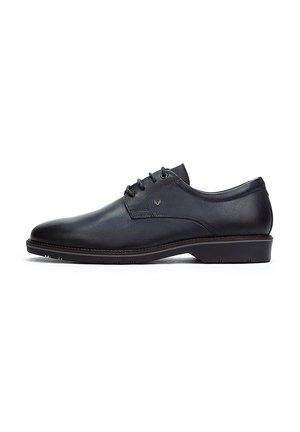 Zapato de vestir de cuero negro con un acabado liso, seis ojales para lazar, un tacón bajo y un branding sutil en el costado.