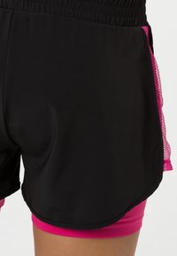 Zwarte sportshorts met een roze mesh accent aan de zijkant, voorzien van een brede elastische tailleband en een gelaagd ontwerp voor comfort.